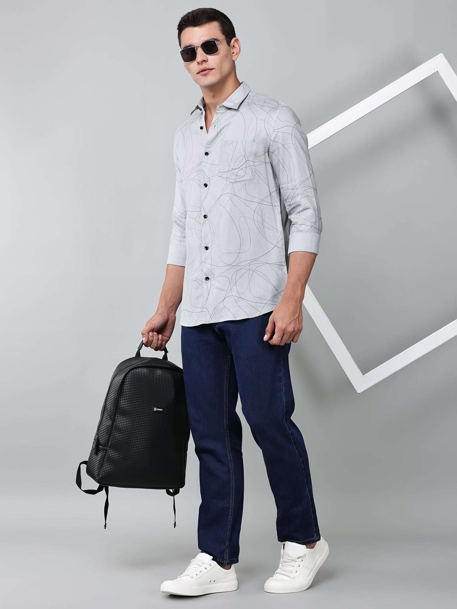 a model wearing a linear drift sketch grey shirt with blue jeans and a black backpack