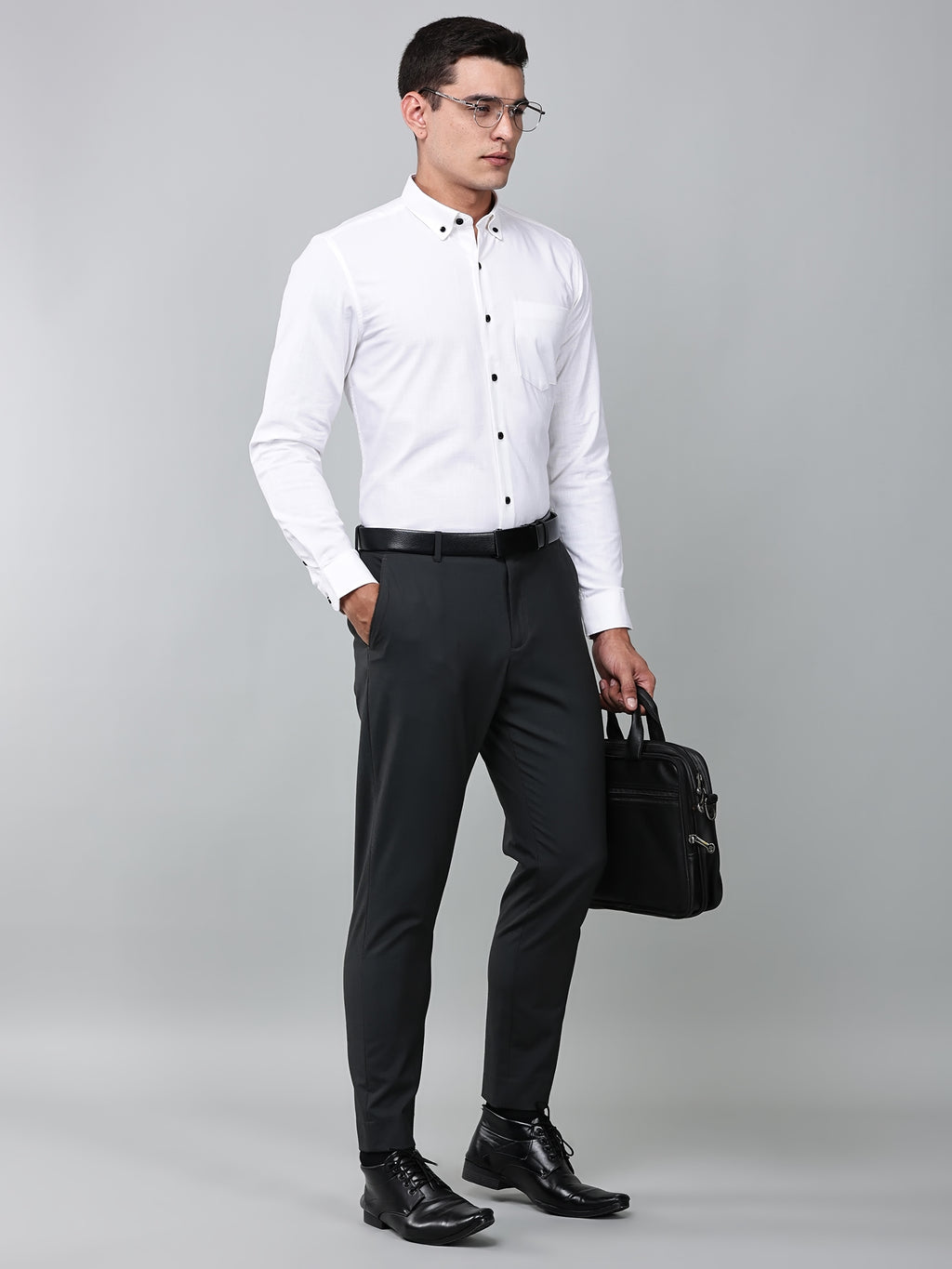 a model wearing a white heritage linen luxe shirt, dark grey trousers, black formal shoes and a laptop bag