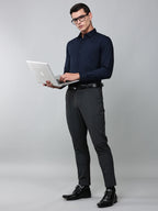 a model wearing a signature textured stretch formal navy blue shirt, grey trousers, black formal shoes, glasses and holding a laptop