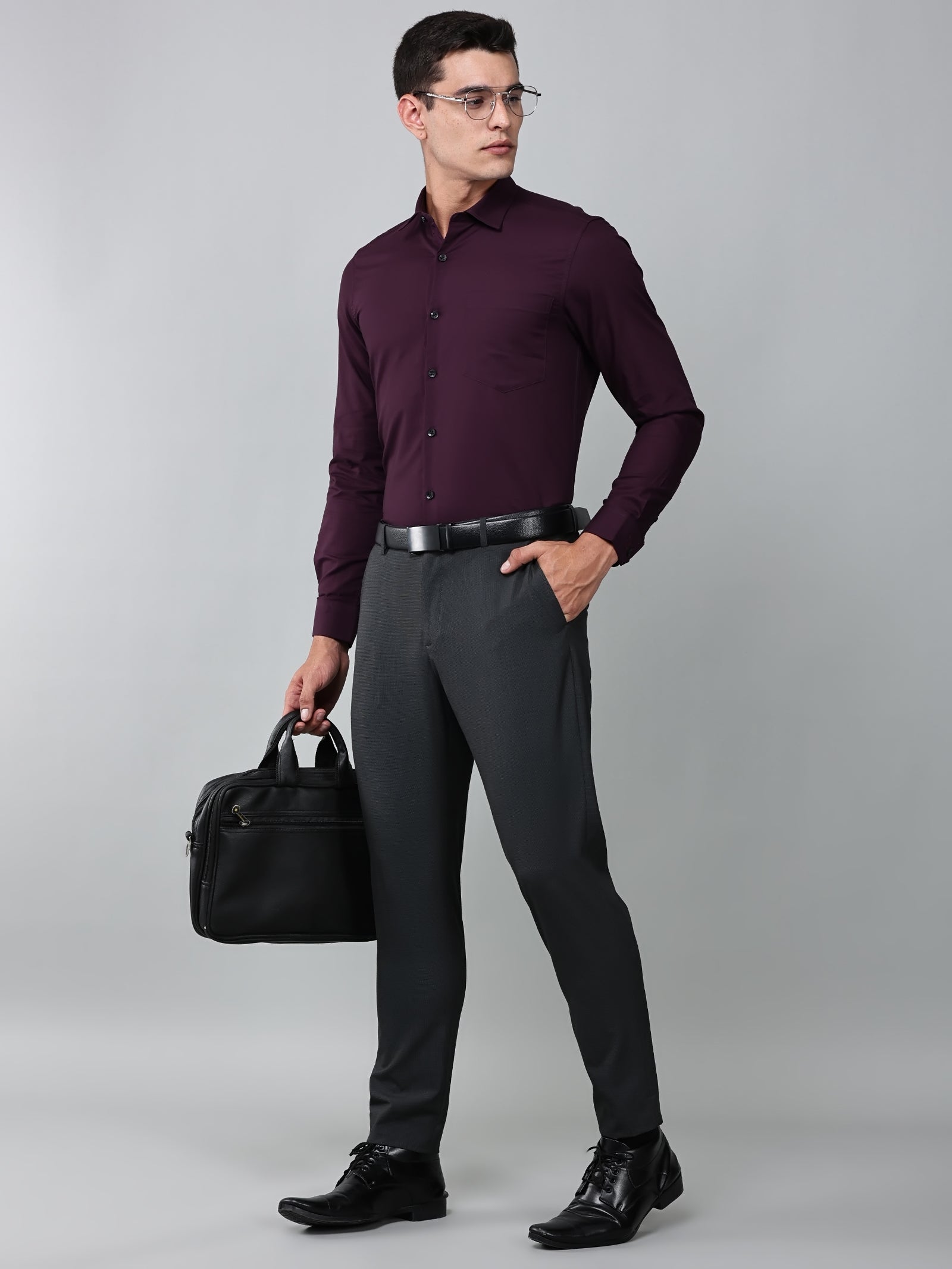 a model wearing a signature textured stretch formal purple shirt, with grey trousers, black formal shoes, and a laptop bag