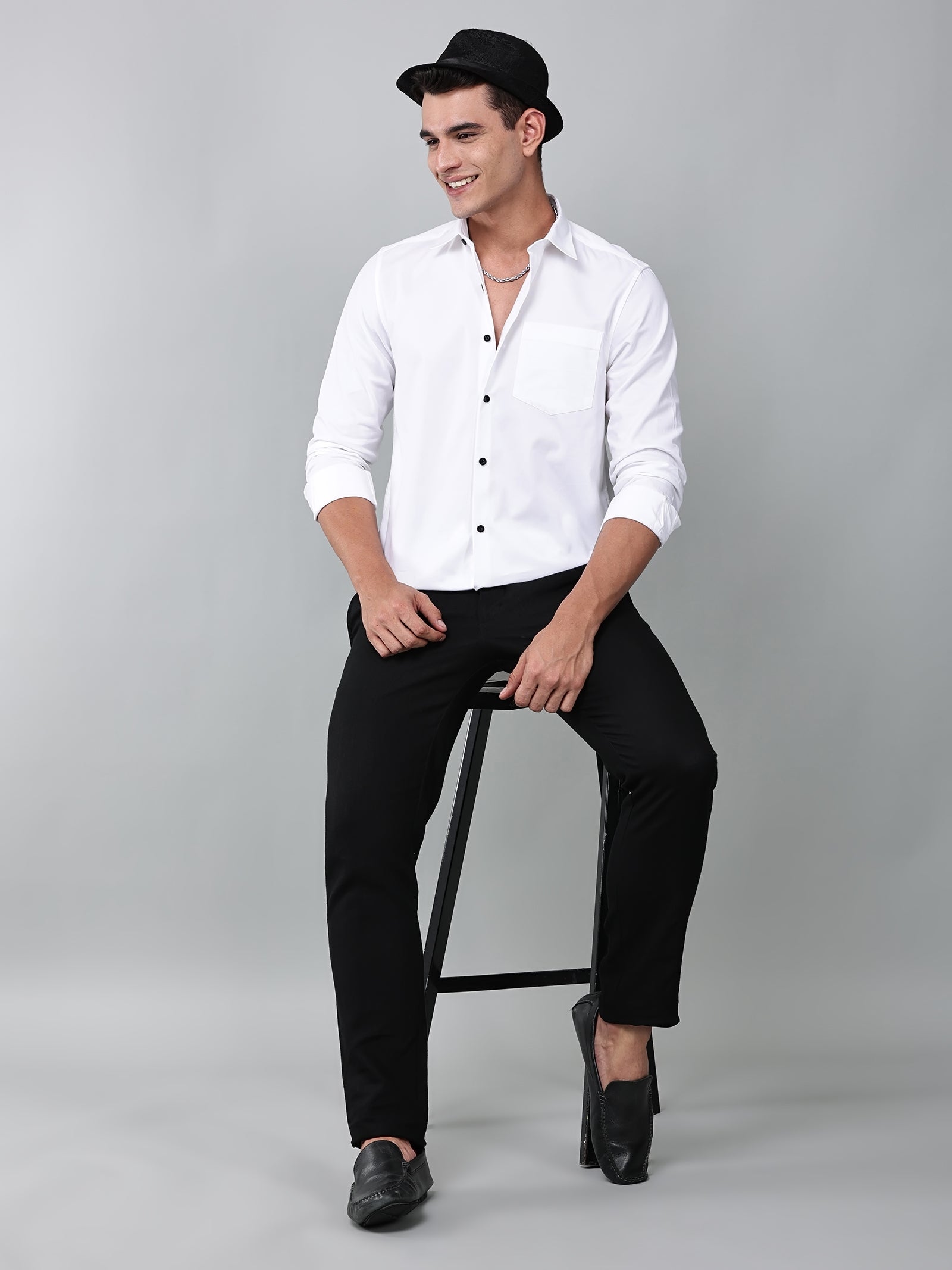 a model wearing a contour textured classy white shirt with black trousers, black loafers and a black hat