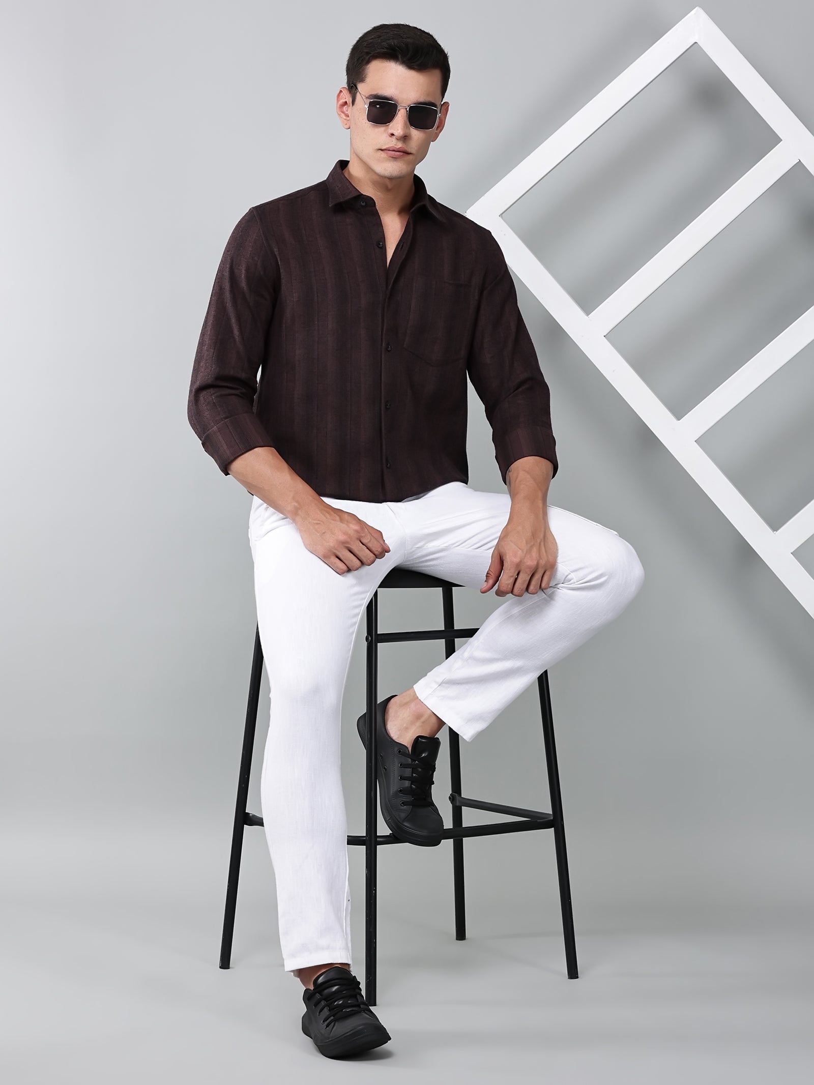 a model wearing a midnight noir (black) maroon shirt with white trousers and black shoes