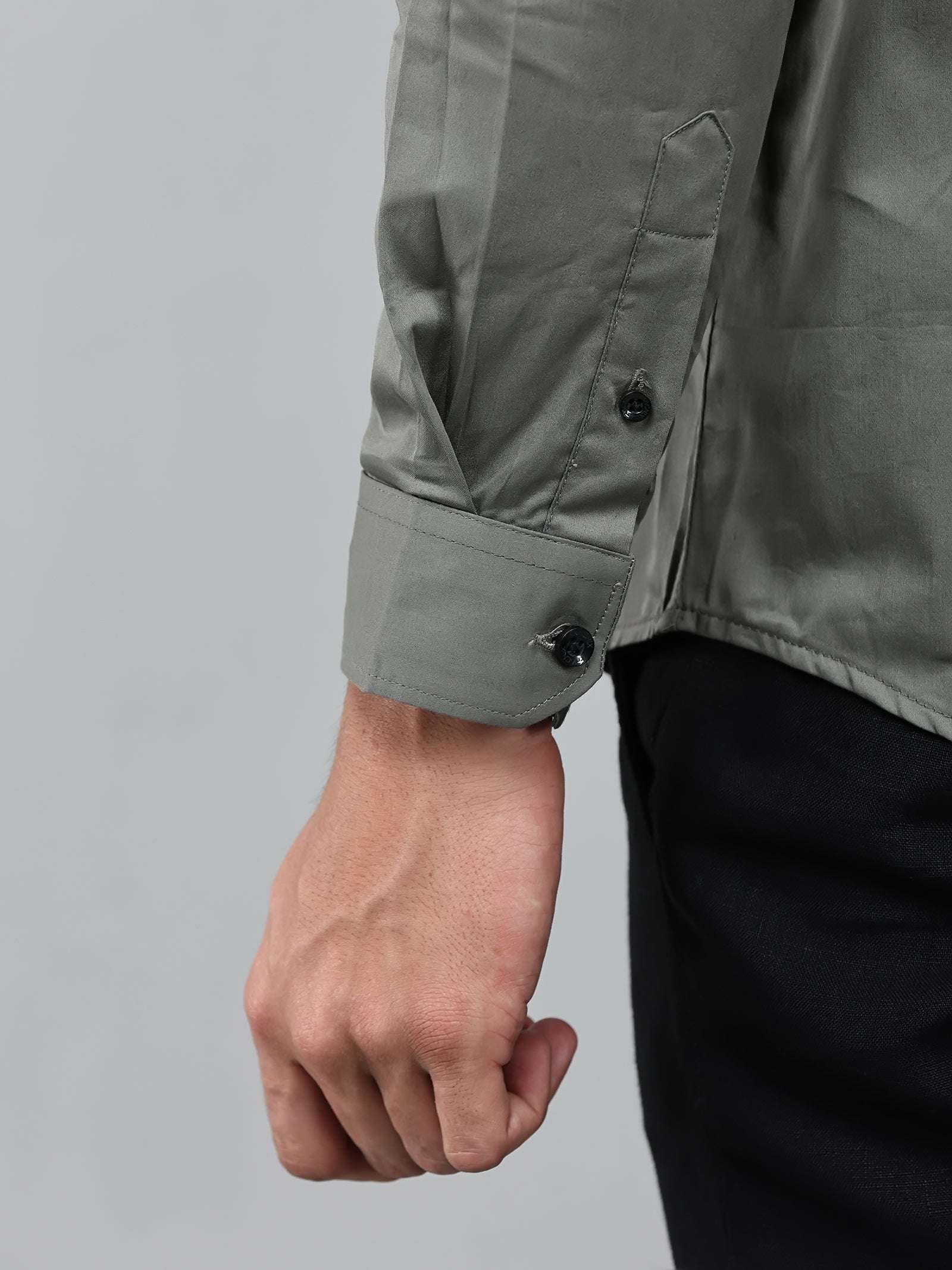 close up shot of the cuff sleeve of the model wearing a luxe satin olive green shirt
